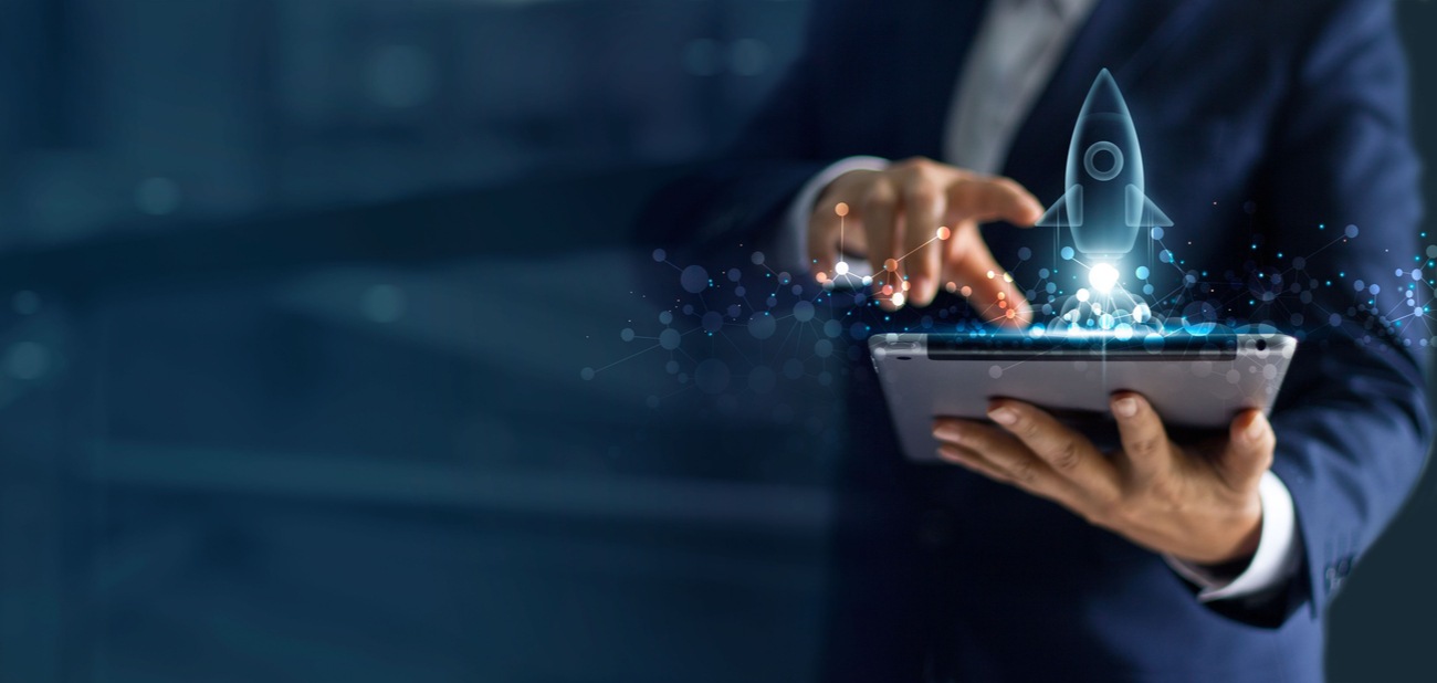 startup-financing2 Businessman holding tablet and icon transparent rocket is launching and soar flying out from screen.