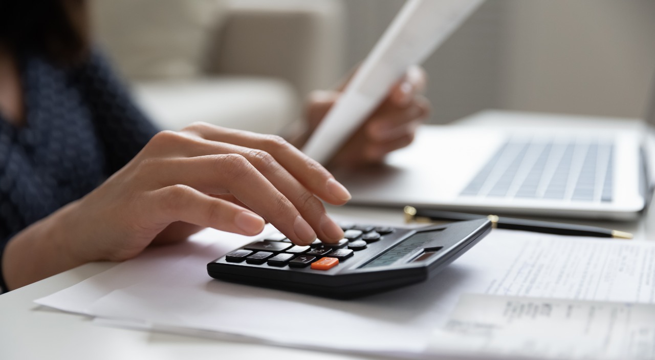 apr-personal-loan Young lady managing monthly banking payments summarizing utility bills and taxes at home.