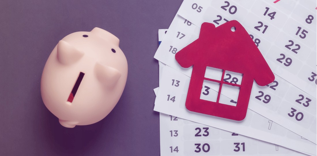 Piggy bank, house figurine with monthly calendar on gray background.