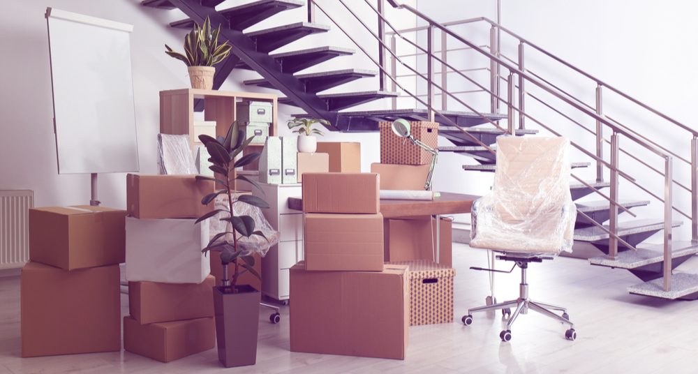 Cardboard boxes and furniture near stairs in office.