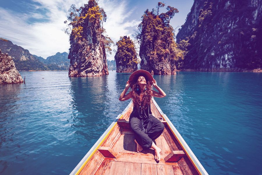 Happy young woman tourist in asian hat on the boat at lake.