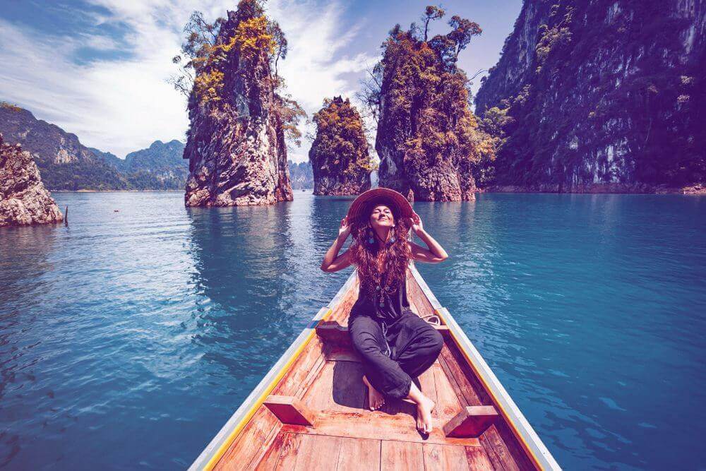 Young woman tourist in asian hat on the boat at lake.