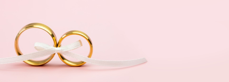 Golden wedding rings on pink background