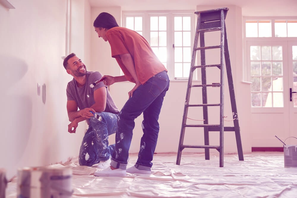 Couple painting walls in new home.