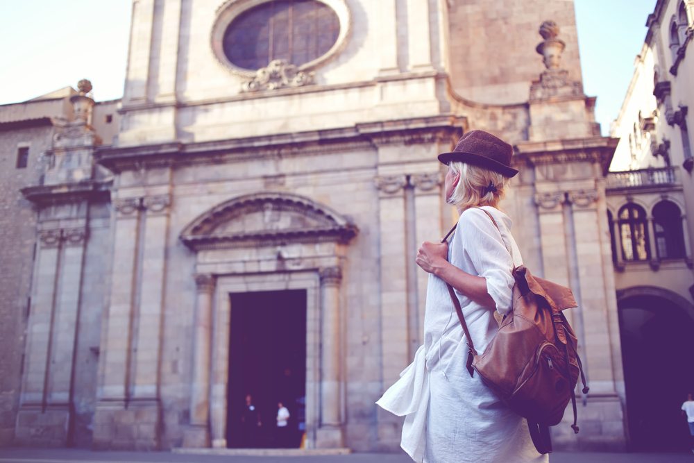 Back view of a young woman traveler with a backpack on her shoulder out sightseeing in a foreign city.