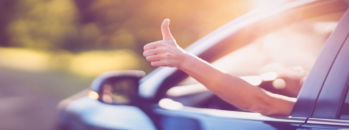 Woman inside her car gesticulate thumb up.