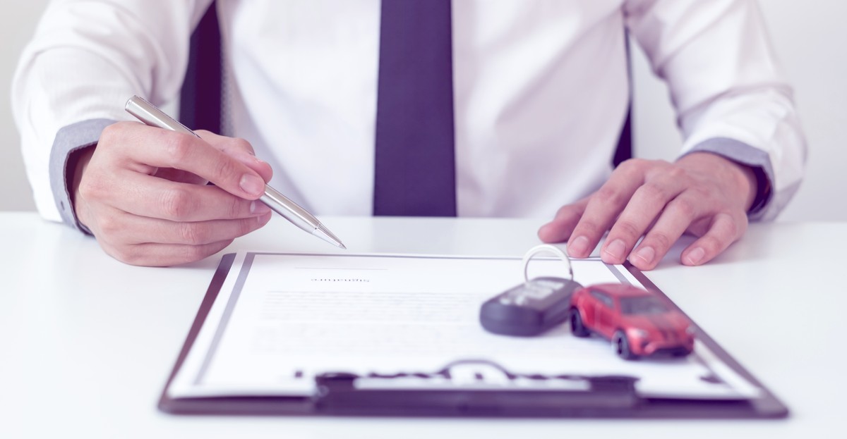 Car dealer businessman signing car insurance document or lease paper.