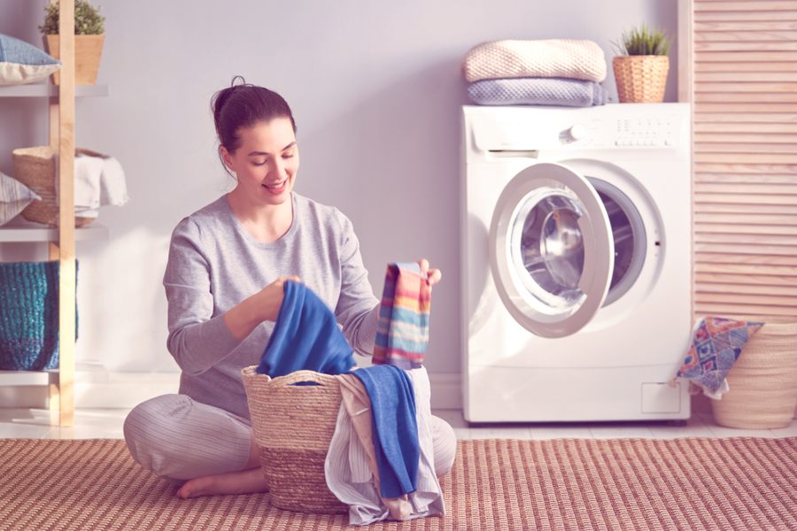 Young woman is smiling while doing laundry at home.