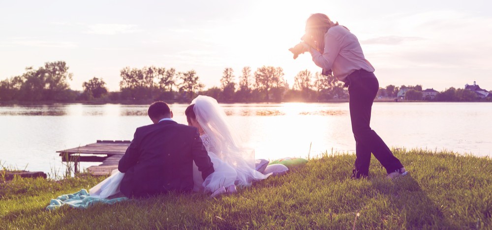 Wedding photographer photographs brides sitting on the lake