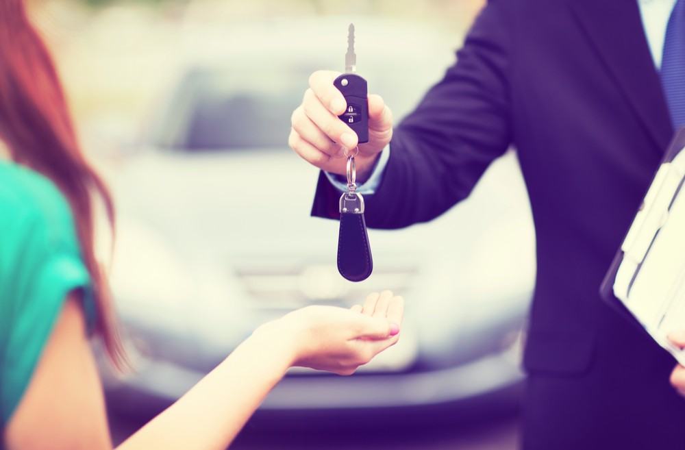 Customer and salesman with car key outside.