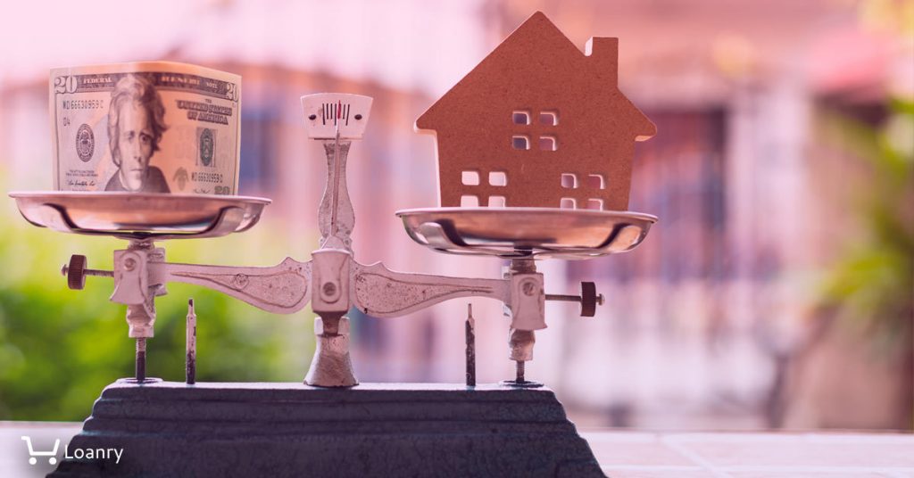 House model and money on weight scale with out of focus home.