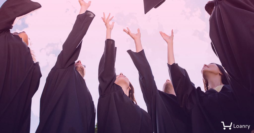 Low angle view of happy group of six young cheerful graduates in black gowns, throwing up their head wear in the air and celebrating.