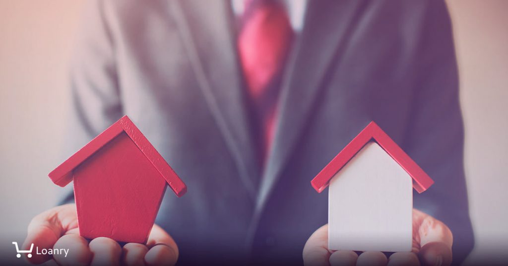 Businessman holding two houses and can not decide choosing the right house