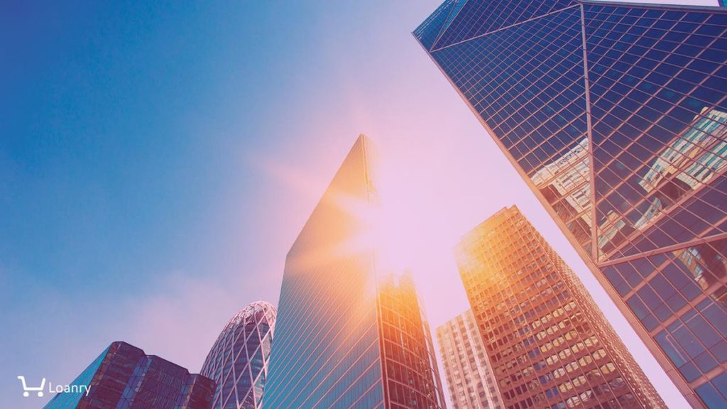 Skyscraper glass facades on a bright sunny day with sunbeams in the blue sky.
