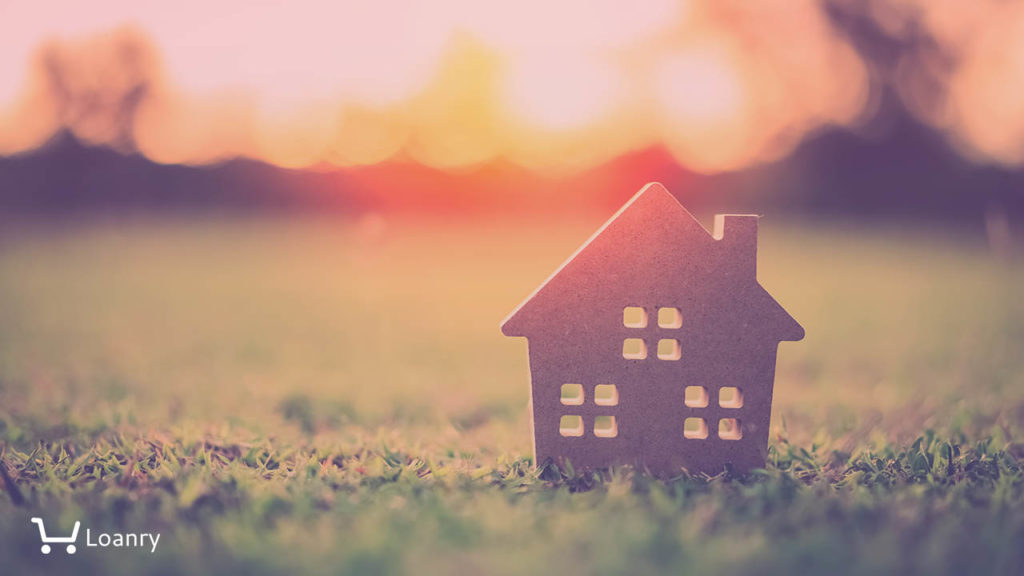 Small model home on green grass with sunlight abstract background