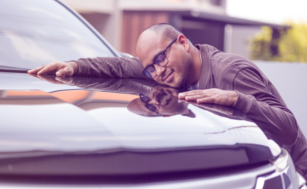 Young man getting the new car. He hugged his car and was very happy.