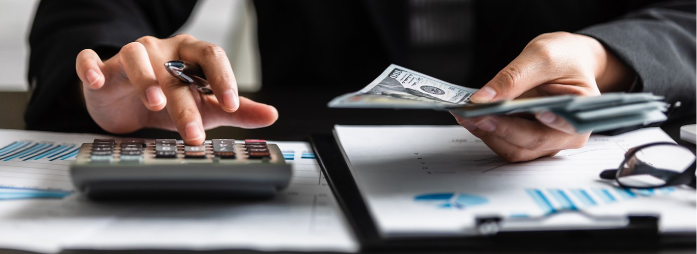 Close up view of businesswomen or accountant counting dollar banknote with using calculator.