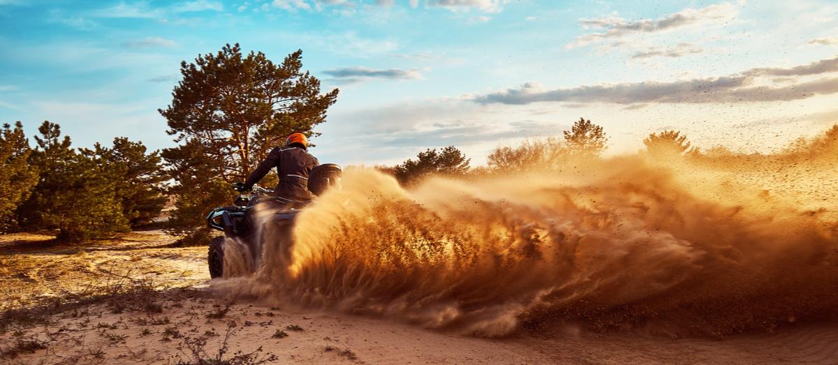 Person riding ATV in sand dunes making a turn in the sand.